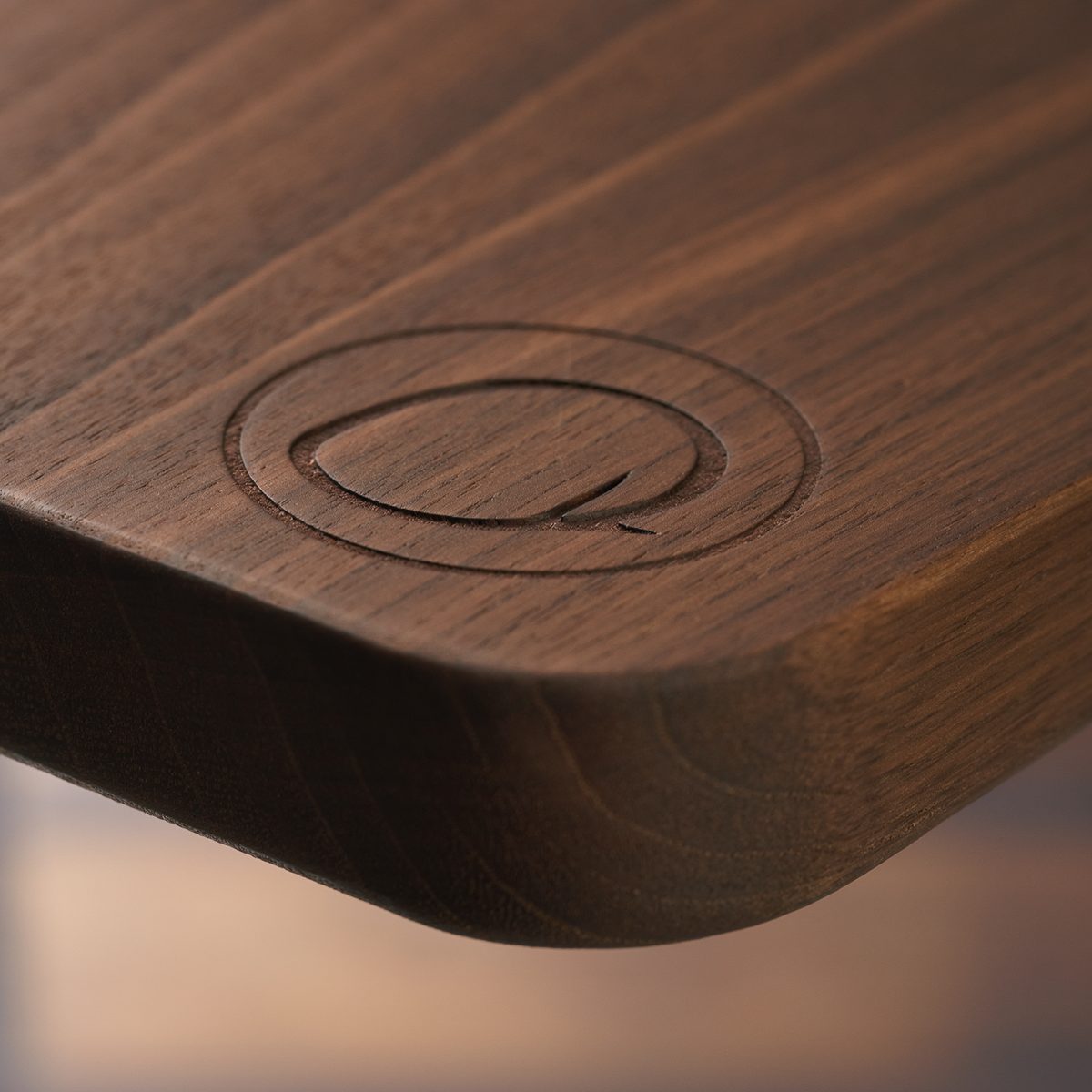 Close-up of dark walnut charcuterie board monogram engraving, wood grain and rounded edge detail