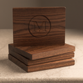 Stacked dark walnut monogram coasters showing matching M engraving, thickness and beveled edges
